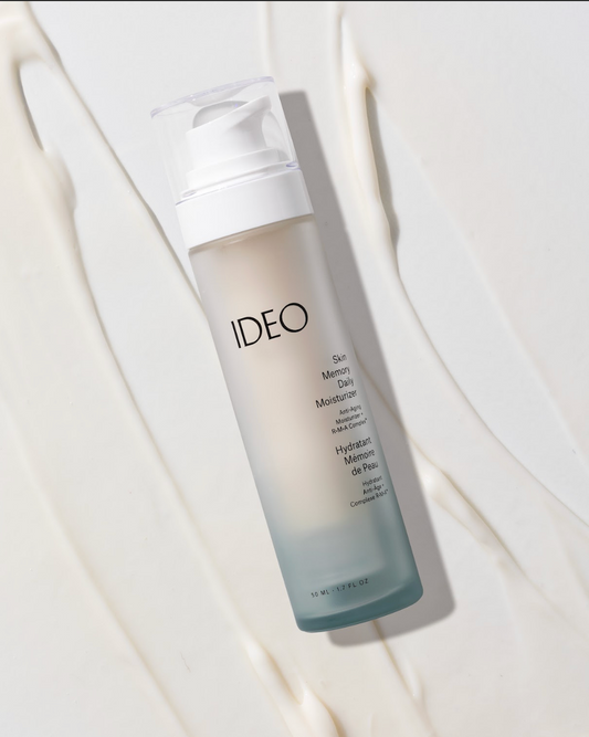 IDEO Skin Memory Daily Moisturizer frosted pump bottle lying beside cream texture swatch flat lay editorial